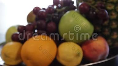 镜头从模糊幻灯片在一个盘子与水果。 菠萝，苹果，红葡萄，柠檬，橘子..
